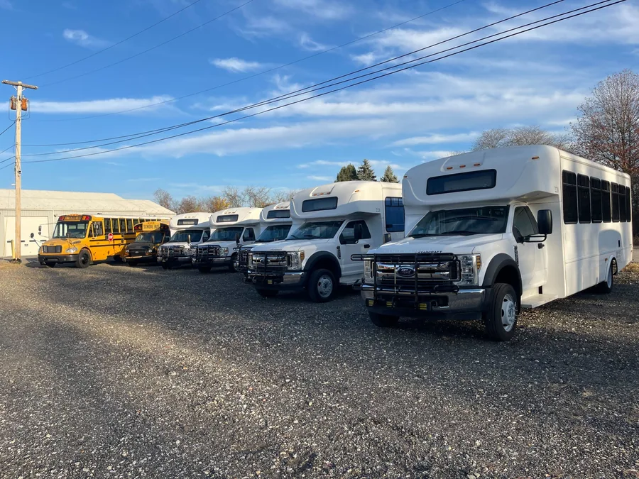 Shuttle buses and school buses lined up on the BusesForSale.com lot