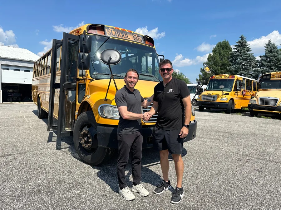 A school bus handed over to its new owner at the BusesForSale.com lot